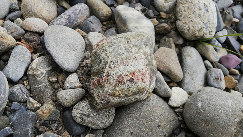 ひび割れが多い緑と赤の入り混じったチャート岩石